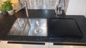 Einbauküche WERT KÜCHE® aus Holz Nachbildung Stein in Weiß Schwarz WERT KÜCHE Gala Musterküche mit Miele Einbaugeräten Muschelweiss & Naturstein schwarz