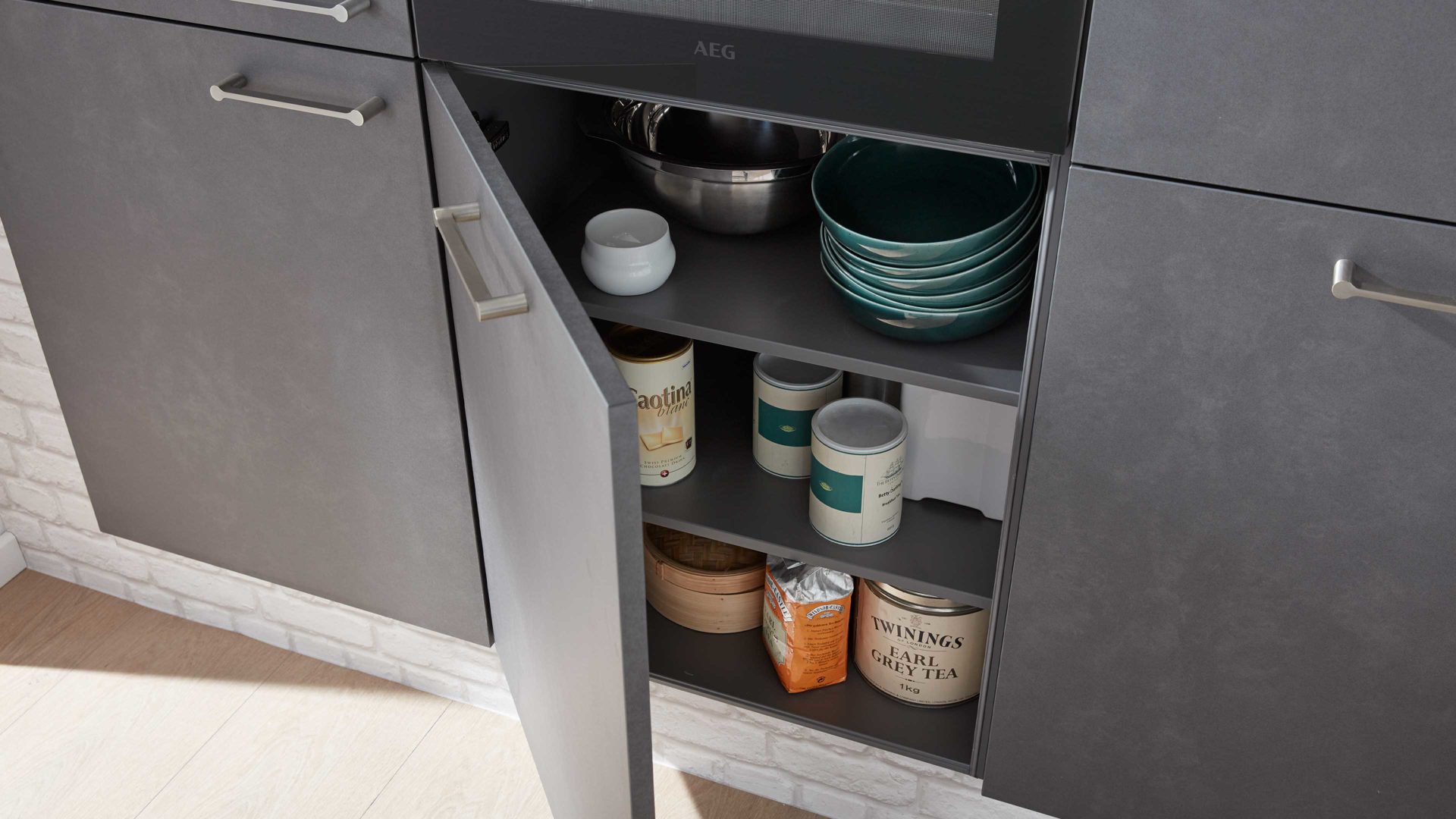 Einbauküche Interliving aus Holz in Grau Interliving Küche Serie 3019 mit AEG Einbaugeräten Weiß & Stahlgrau – zweizeilig