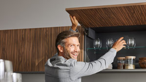 Einbauküche Interliving aus Holz in Schwarz Interliving Küche Serie 3076 mit Miele-Einbaugeräten Mattschwarz & Stripe Wood Choco - dreizeilig