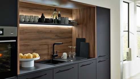 Einbauküche Interliving aus Holz in Schwarz Interliving Küche Serie 3055 mit AEG Einbaugeräten Mattschwarz & Vulkaneiche  - dreizeilig